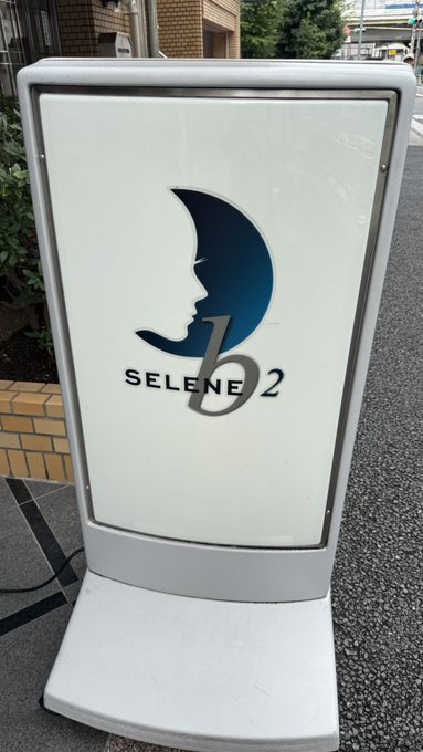 An illuminated outdoor sign displaying the "SELENE 2" logo with a stylized crescent moon and face profile design.