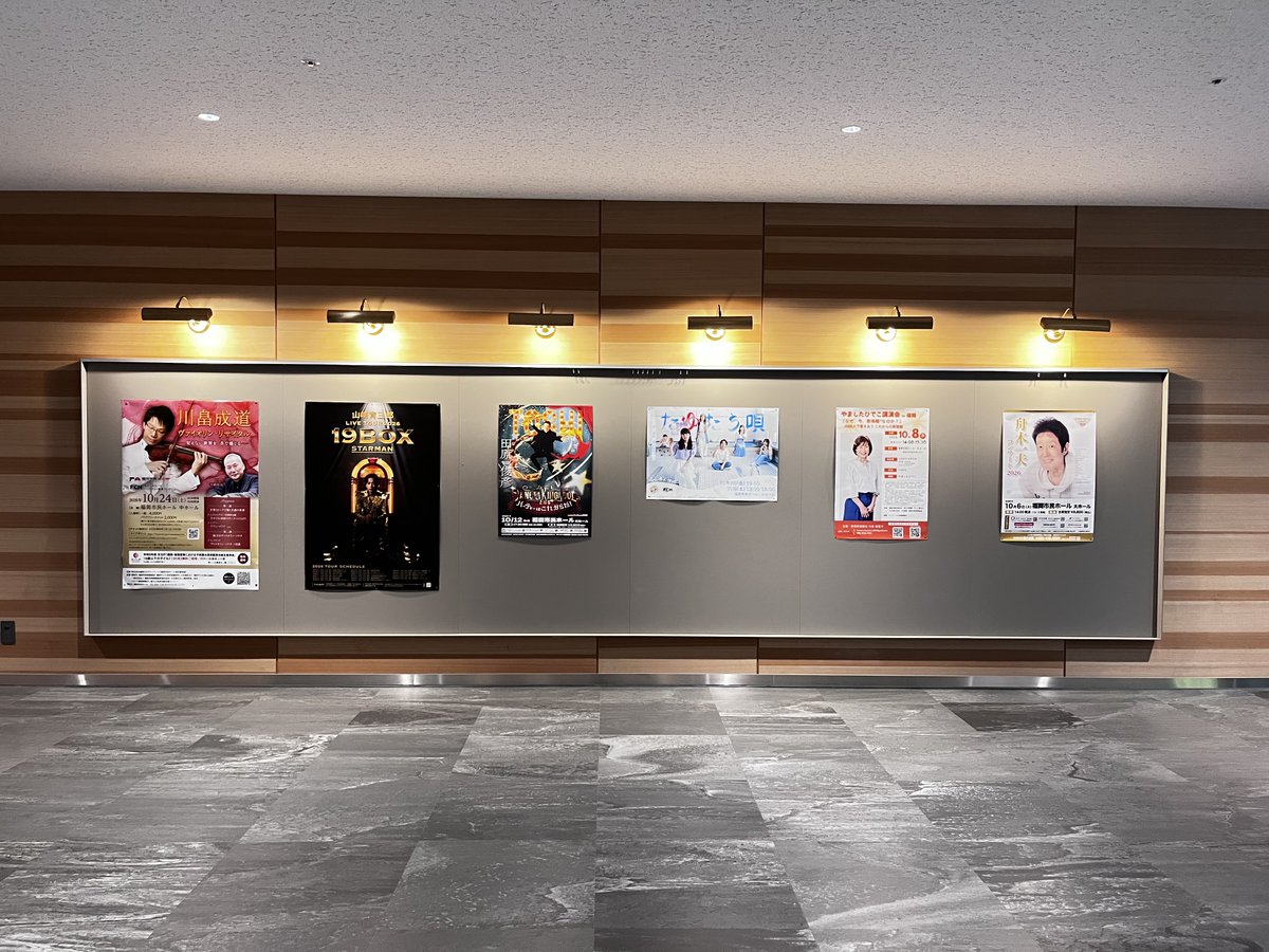 fuk_civic_hall's tweet photo. 今日は、市民ホール2Fにあるギャラリーの写真をお届けします。

このギャラリーには、市民ホールで開催されるコンサート＆演劇のポスターや福岡市及び近郊に住む作家さんたちの作品を飾ったりしています。

一番右端にあるのは、10/24（土）に中ホールで開催する川畠成道さんのリサイタルのポスター🥰

中央は、10/9（金）～10/10（土）に開催する劇団「最中（もなか）の最中（さなか）」のポスターです。

この2つの公演は、絶賛チケット販売中✨
購入希望の方は、福岡市民ホールのHP「お知らせ」を
ご覧くださいね😉

#福岡市民ホール　#川畠成道　#寺嶋陸也
#最中の最中