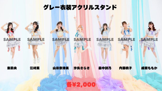 An advertisement for AKB48 acrylic stands featuring seven members in gray outfits, priced at ¥2,000, with names listed in Japanese including 東莉央, 江崎光, 山岸奈津美, and others.