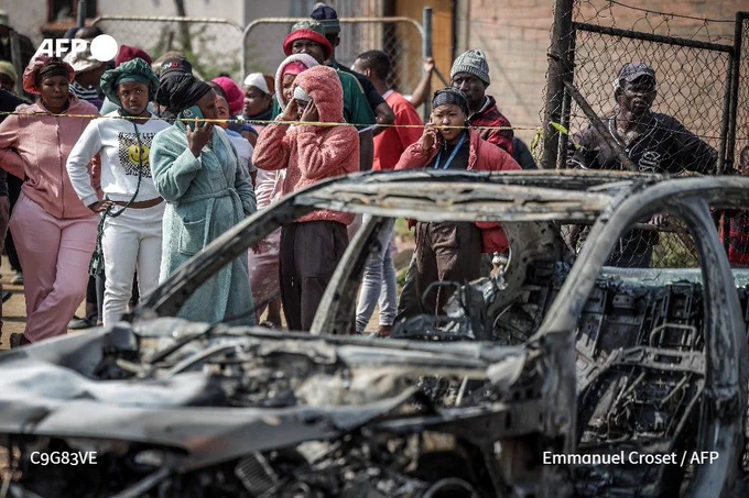 Residents stand behind police tape near the scene where gunmen armed with assault rifles stormed a bar in Johannesburg, on September 27, 2026.