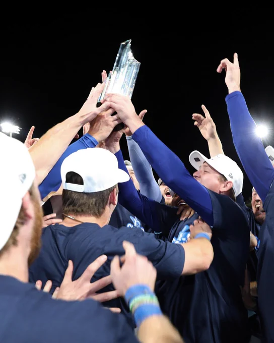 Players gather around and raise the Triple-A championship trophy in celebration.