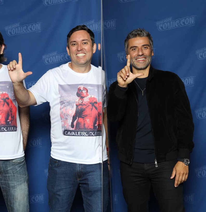 SiteJamesons's tweet photo. DO LULA! O ator Oscar Isaac, que interpreta o herói Cavaleiro da Lua no MCU, fazendo o L ao lado de fãs que vestem a camiseta do "Cavaleiro do Lula".

Foto: @RegisRezende