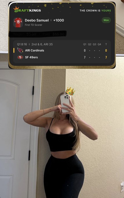 A woman in a black crop top and leggings poses for a mirror selfie with a crown emoji, celebrating a winning DraftKings sports bet shown at the top — Deebo Samuel scored first for the SF 49ers against the ARI Cardinals, securing a $55.00 win on a $5.00 wager.