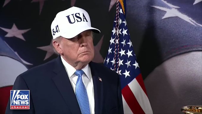 A Fox News Channel broadcast showing Donald Trump wearing a white 'USA 45-47' cap and dark suit, standing in front of an American flag.