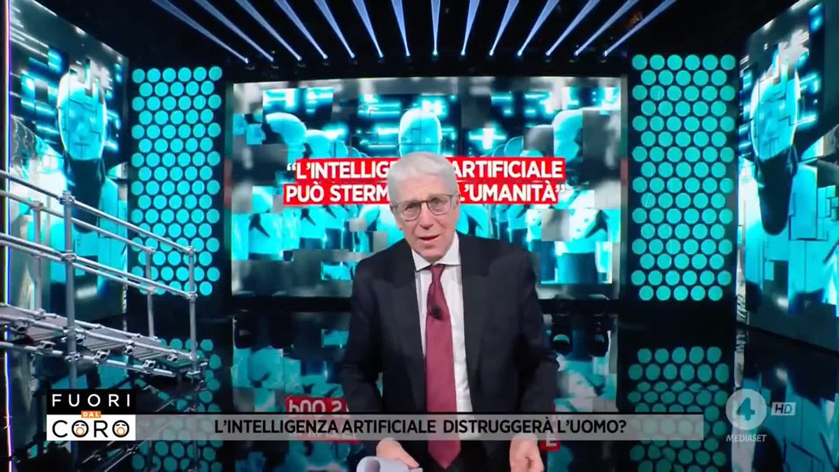 A news segment from 'Fuori dal Coro' featuring an older male anchor in a suit with text on screen reading 'L'INTELLIGENZA ARTIFICIALE DISTRUGGERÀ L'UOMO?' and 'L'INTELLIGENZA ARTIFICIALE PUÒ STERMINARE L'UMANITÀ'.