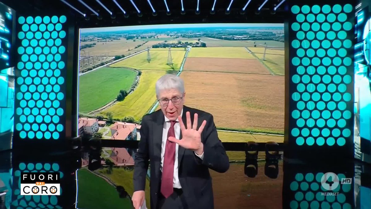 An older man in a suit and red tie gestures on a TV studio set with a rural landscape backdrop; logos for 'FUORI DAL CORO' and 'MEDIASET 4 HD' appear on screen.