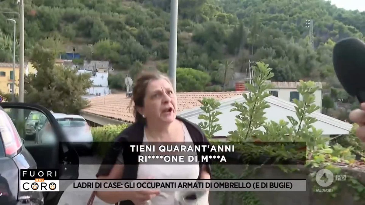 A screenshot from the Italian TV show 'Fuori dal Coro' showing a woman being interviewed, with subtitles reading 'TIENI QUARANT'ANNI RI****ONE DI M***A' and a banner reading 'LADRI DI CASE: GLI OCCUPANTI ARMATI DI OMBRELLO (E DI BUGIE)'.
