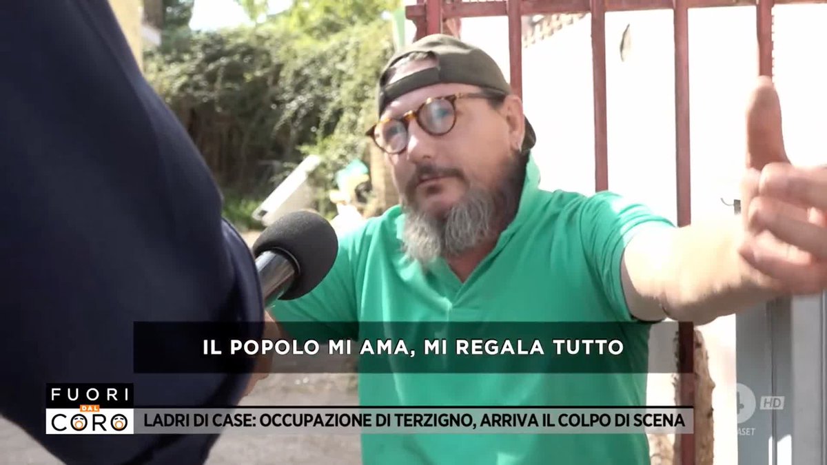 A bearded man wearing glasses, a backward cap, and a green polo shirt gives a thumbs-up during an interview, with the caption 'IL POPOLO MI AMA, MI REGALA TUTTO' and the banner 'LADRI DI CASE: OCCUPAZIONE DI TERZIGNO, ARRIVA IL COLPO DI SCENA' on 'Fuori dal Coro'.