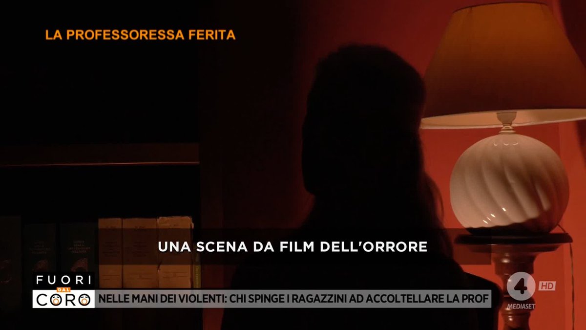 A TV news segment from 'Fuori dal Coro' (Mediaset) showing a silhouetted figure in a red-lit room with the headline 'LA PROFESSORESSA FERITA' and 'UNA SCENA DA FILM DELL'ORRORE'.