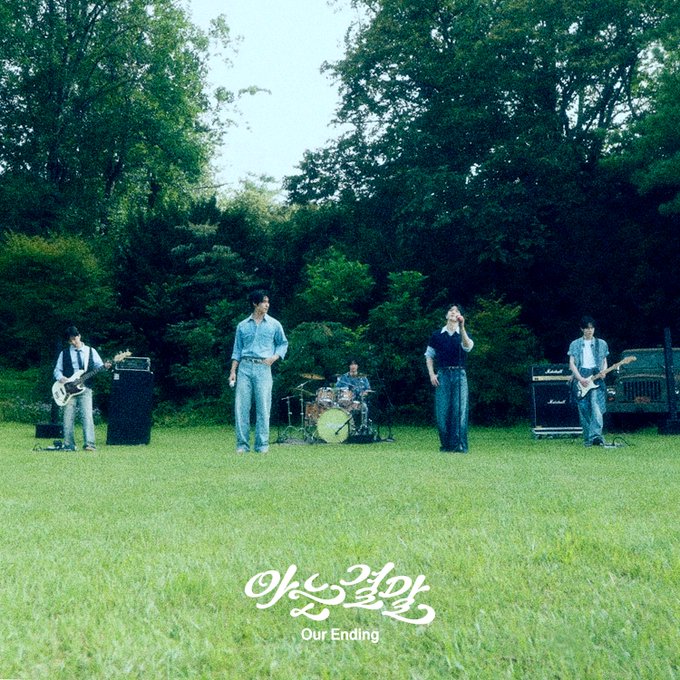 A band of five members performs on a grassy field surrounded by lush green trees, with Korean text '아는결말' and English 'Our Ending' displayed at the bottom.