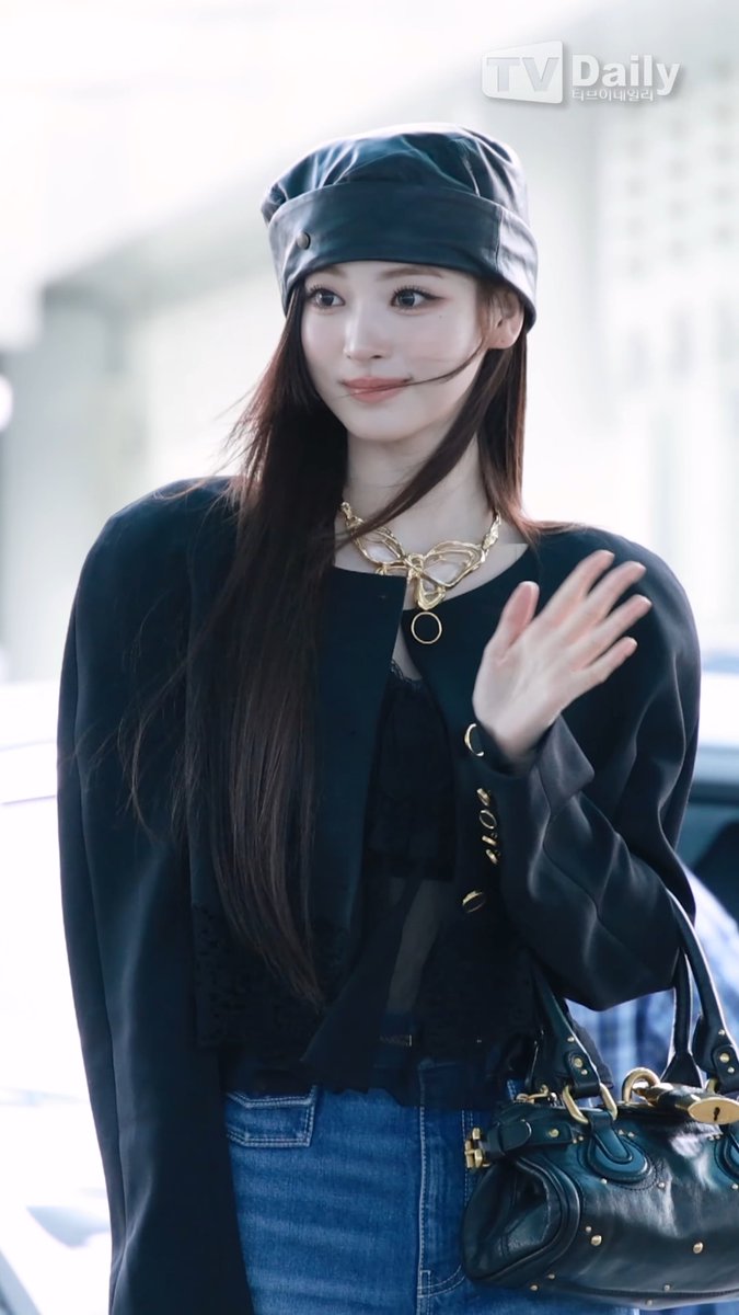The image shows a stylish woman wearing a black bucket hat, a chunky gold chain necklace, a black blouse, and carrying a black leather handbag while waving. The "TV Daily" watermark is visible in the top right corner, suggesting this is an airport or celebrity fashion photo, which aligns with the post referencing "Chloe Princess Miaow Anna" — likely a fan nickname combining her name with the luxury brand she's wearing (Chloé).