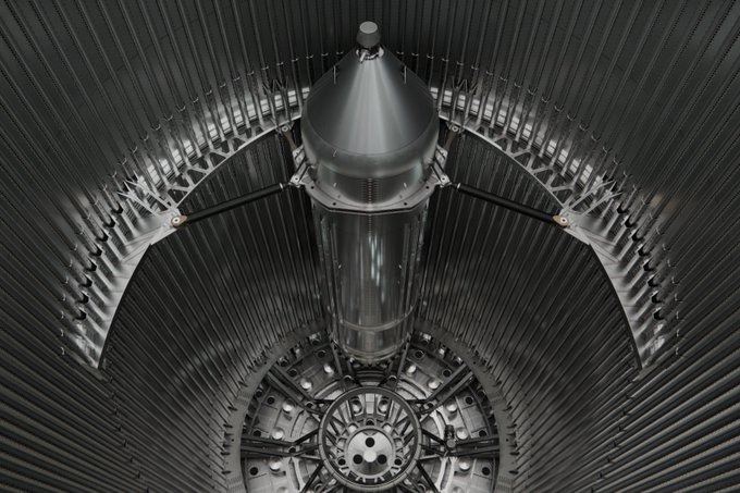 A close-up view of a rocket engine's lox (liquid oxygen) header, featuring a central domed structure with radiating metallic feed tubes arranged in a symmetrical, ribbed pattern. The intricate engineering showcases the plumbing system responsible for delivering liquid oxygen to the combustion chamber.