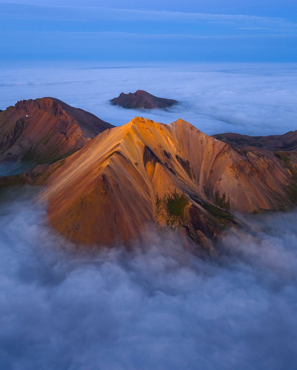 Lemes95's tweet photo. East Iceland, last July: above the fog at midnight on a surreal summer night. One of my favorite evenings of the summer. The sun set just before midnight, and the remaining glow turned the mountains bright orange beneath a twilight-blue sky ⛰️

For o... https://t.co/7HhKaxCeRC