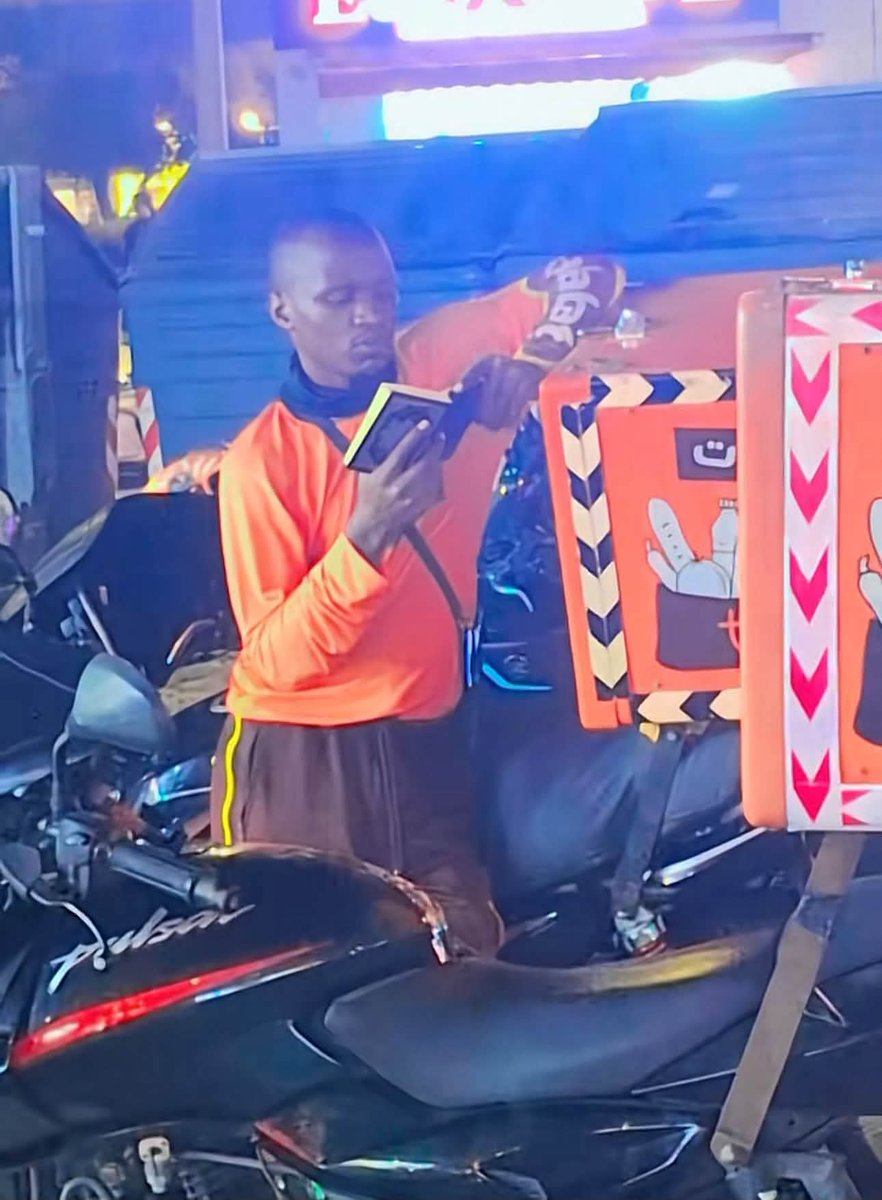 AhmadX_Official's tweet photo. A Nigerian delivery rider in Dubai reportedly became the center of attention after someone filmed him late at night, waiting for his next order while reading the Qur’an beside his motorcycle.

What made the scene unusual was the small Qur’an box he had arranged near the front of his bike. Whenever there was a break between deliveries, he would take the Qur’an out and read.

When asked why he carried a physical Qur’an instead of simply reading from his phone, his answer was deeply moving.

He reportedly explained that he is a Hafiz of the Qur’an and regularly recites it during Ramadan. He had memorized the Qur’an through constant revision, not from a phone, and continues reading many chapters every day alongside his work so that he does not forget what he has memorized.

The video reportedly spread widely and eventually reached Dubai authorities. Claims circulating online say that he was later recognized and rewarded for his dedication and sincerity, with some posts stating that he received AED 50,000.

Whether every detail of the viral story is accurate or not, one lesson remains powerful:

Do not let your circumstances make you forget the Book of Allah.

He was waiting for a delivery order, but perhaps he was also preparing for something far greater.

May Allah preserve the Qur’an in his heart, increase him in sincerity, and bless his work and his life.
