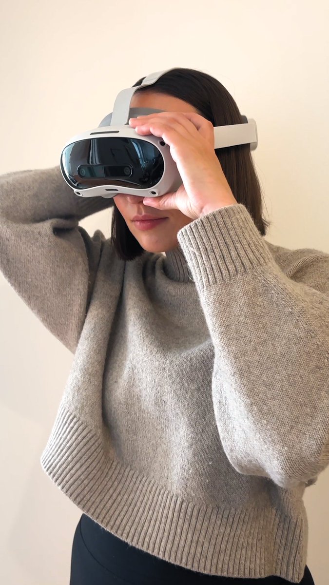 A woman in a cozy beige sweater adjusts the head strap of a white virtual reality headset, preparing to dive into an immersive experience. The image visually echoes the post's "small adjustments" phrase, capturing the final moments of setup before gameplay begins.