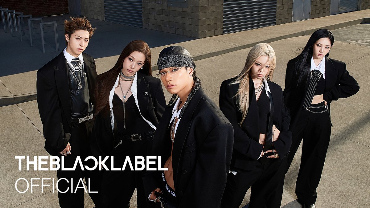 A promotional image for THEBLACKLABEL OFFICIAL featuring five people in black suits and stylish outfits posing on a concrete surface.