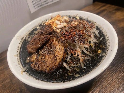 ramenmatakokode's tweet photo. ㊗️1周年、1日限定ラーメン解禁㊗️

10月10日のみご提供するラーメン、
その名も——
『漆黒に染まりし黒羅亜麺』❗️
※限定200食、無くなり次第終了です。

男性スタッフ中心に、
「インパクト」「特別感」「1周年感」など色々考えた結果、こんな感じになりました…察してくださ���。

当日は片手に包帯を巻いて、眼帯しながら食べたくなりそうな一杯ですが、
味の方はめちゃくちゃ自信あります🍜🔥

黒胡麻と自家製ラー油を使用した、
黒く、香り高い濃厚スープ。
(黒担々のようなイメージ)

そして、なんといっても特別な方法でこの日だけ実現する「黒麺」。

見た目だけじゃなく、しっかり美味い。
1周年だからこそ作れる、1日限りの一杯です。

せっかくなので、たくさんの方に食べてもらいたいです！
🔁こちらの投稿をリポストしてご来店いただいた方には、
【1周年限定ステッカー】をプレゼントします🎁
(10/6〜10/12までの営業でリポスト画面をスタッフにお見せください✨)

いろんな意味で黒歴史になっちゃいそうですが、良かったら是非拡散してください🙇‍♂️