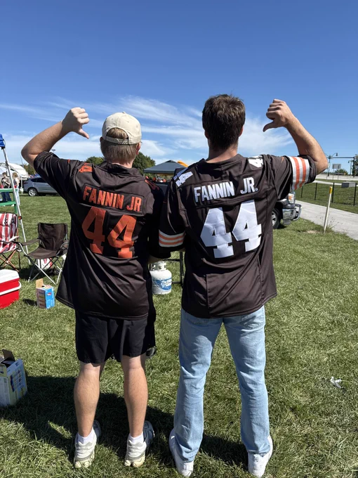 Two BGSU alumni stand with their backs to the camera, showing off matching Fannin Jr. football jerseys.