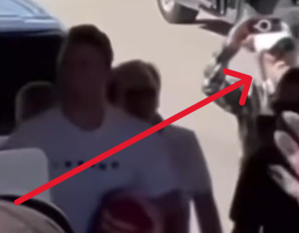 AlexandriaMcCue's tweet photo. The visual anomalies carry right over into the hands when you track the footage closely and in slow motion. Look at the red box with the blue arrows. The hand geometry is a completely distorted, dark gray mass. It doesn't quite mimic human biology. They were clearly operating under an unexpected time crunch because the plan did not go as expected. The rush job shows.

To be perfectly clear, the real Butch Shady was actually on-site the entire time. There's no debating his physical presence. But he doesn't have an unrendered digital void for a face or glitched gray geometric masses for hands.

The mechanism here is clever but sloppy. They used the real Butch walking around after Charlie was taken down as a baseline narrative shield to make us assume the figure at the perimeter was also him. But physical geometry and rushed pixels don’t lie, no matter how much digital paint they throw over the timeline under pressure.

They needed Erika scrubbed from that specific perimeter narrative, but they left the digital receipts all over the footage.