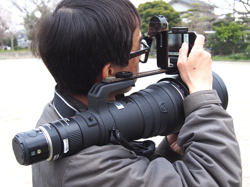 ASUS_ZenBlog's tweet photo. OLYMPUS AIRといえばこの記事。換算1200mmの超望遠を肩に担ぐスタイルで、シャッターとファインダーはWi-Fi接続したiPhoneで行う。レンズ後端に付いたちっちゃい塊がカメラ本体にはとても見えない。 https://t.co/lOfYmU2Kuk