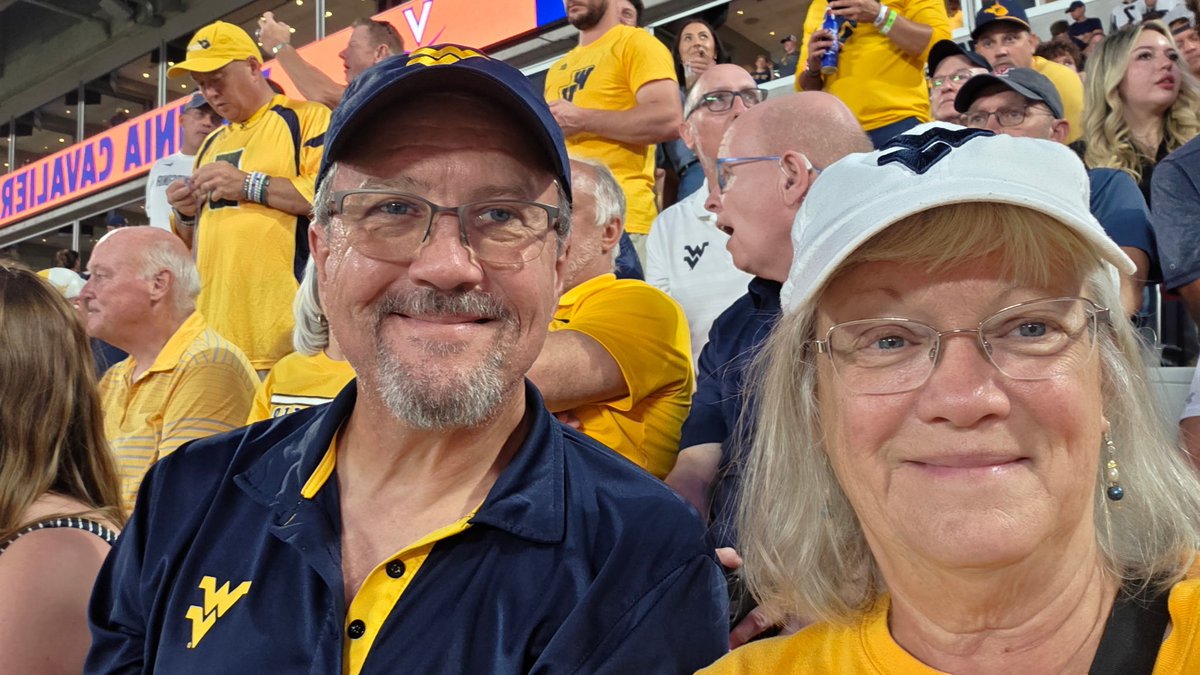 WVU_GBE's tweet photo. We wanted to give a huge thank-you to our Ultimate Mountaineer Football Experience raffle winners, Mike and Suzanne! We were thrilled to send these Mountaineer fans to Charlotte, NC, to see our big win over UVA in person. Thank you for supporting Gold &amp; Blue Enterprises! https://t.co/hzLDaDk4Is