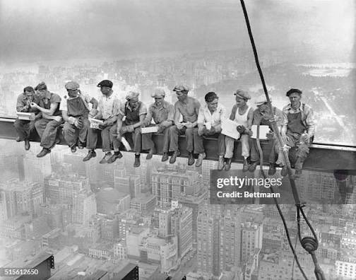 Black and white historical photograph showing ironworkers having lunch while sitting on a steel beam high above a city, famously known as 'Lunch atop a Skyscraper'.
