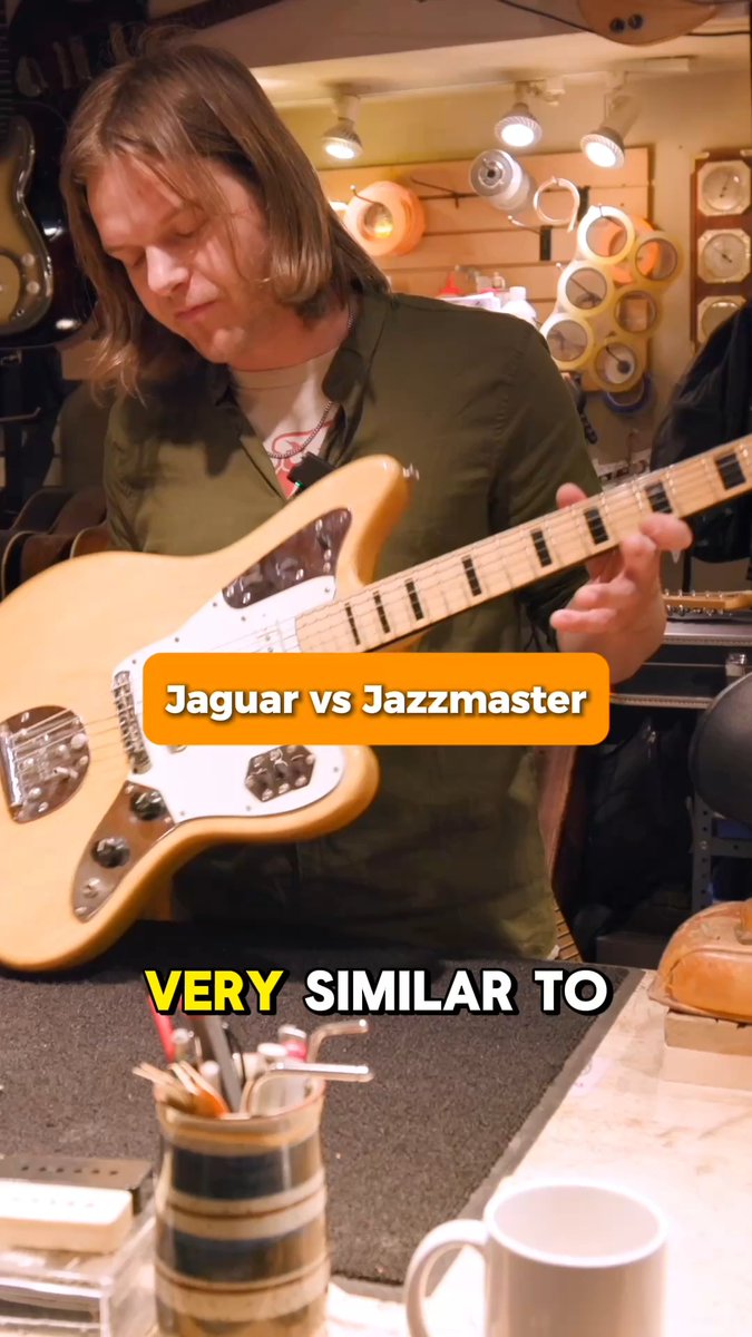 A person plays an electric guitar in a workshop, with text overlays reading 'Jaguar vs Jazzmaster' and 'VERY SIMILAR TO'.