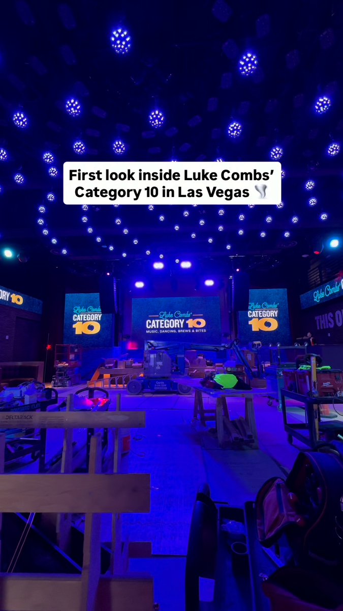 An interior view of Luke Combs' Category 10 venue in Las Vegas with text overlay 'First look inside Luke Combs' Category 10 in Las Vegas,' showing blue lighting, screens displaying 'Luke Combs' CATEGORY 10 MUSIC, DANCING, BREWS & BITES,' and construction equipment.