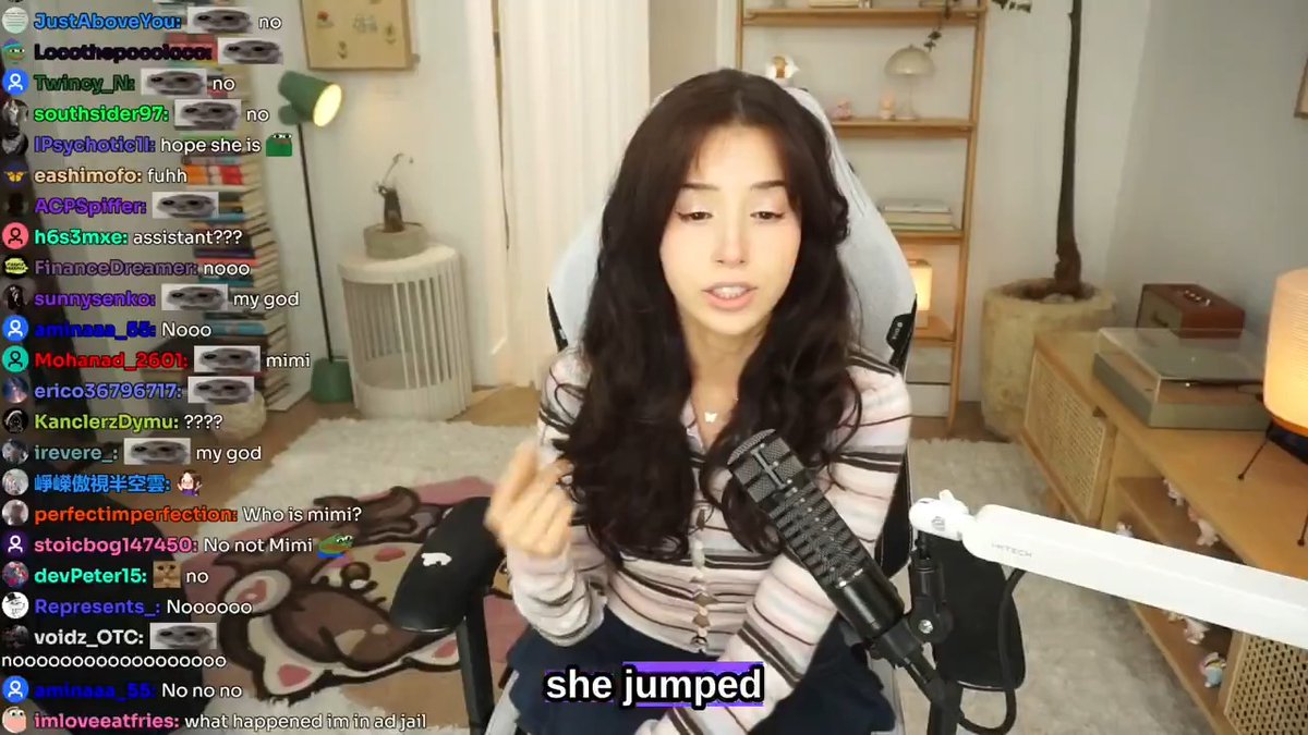 A streamer with long dark hair sits in a gaming chair with a microphone, while chat messages scroll on the left and subtitles read "she jumped" at the bottom.