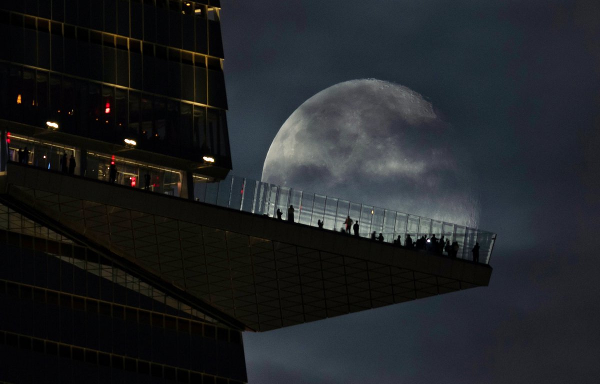 GaryHershorn's tweet photo. A 93 percent illuminated waning gibbous moon rises behind the EdgeNYC observation deck at Hudson Yards two days after the full Harvest Moon in New York City, Monday evening #newyorkcity #nyc #newyork #moon @edgenyc https://t.co/hyCjlmkfJm