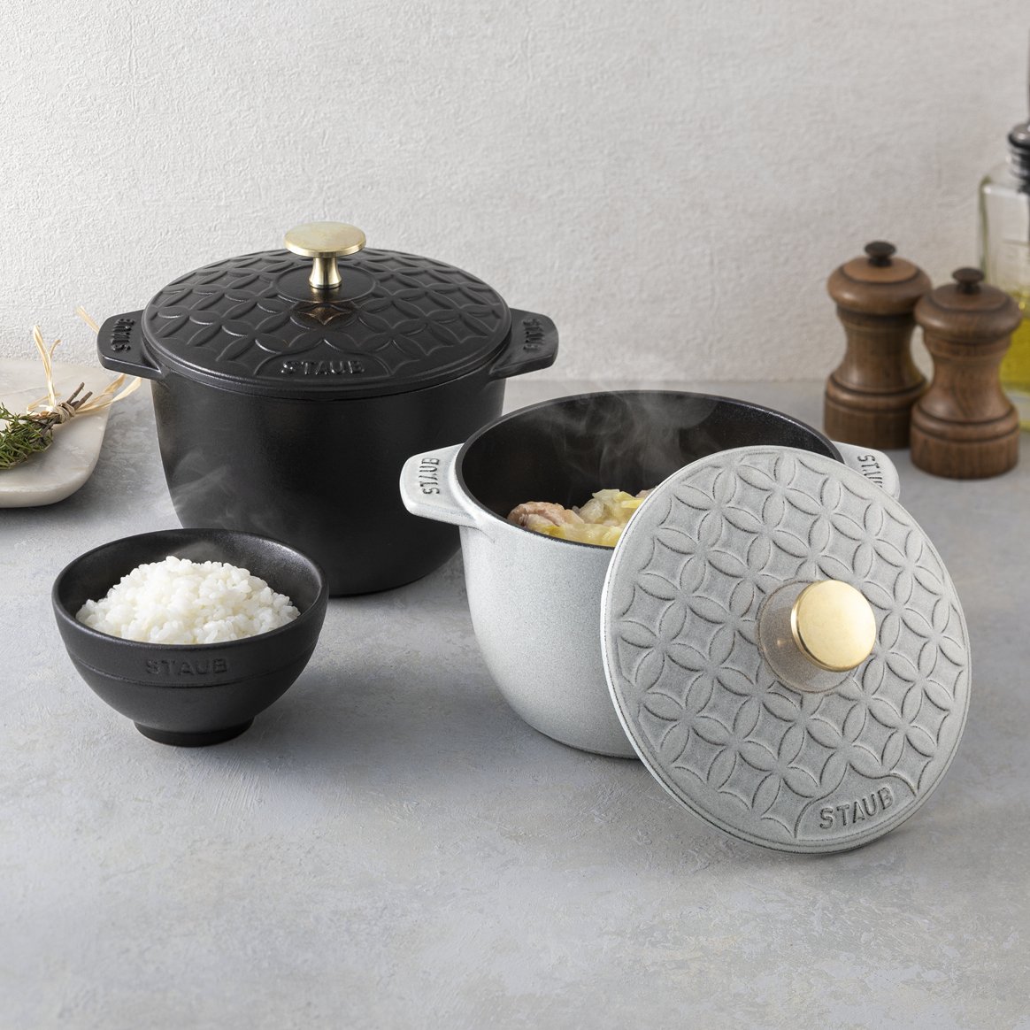 StaubJapon's tweet photo. 【世界先行発売 : 日本の伝統美をまとった、特別なココットが登場】
株式会社dinos との共同企画による、スペシャル ココット「ストウブ 七宝 リミテッドエディション」が発売となります。
https://t.co/sicIXYOpRW

人気シリーズ「ラ・ココット de GOHAN」の蓋に、日本の伝統紋様である七宝文様をあしらい、ストウブならではの機能性・デザイン性を融合しました。 カラーはブラックとカンパーニュの2色をご用意。

七宝文様は、円満・調和・繁栄への願いが込められた縁起の良い吉祥文様。毎日の食卓にはもちろん、結婚祝いや新築祝いなど大切な方への贈り物にもおすすめです。

さらに、同色のココットを刺繍したノブミトンもセットでご用意。カンパーニュカラーのノブミトンは本企画向けの新色です。

2026年10月1日（木）よりディノスオンラインショップとカタログ「dinos」（10月27日(火)発行）にて発売開始。

日本の伝統美とストウブのクラフトマンシップが出会った特別なココットを、ぜひお楽しみください。

* ディノスオンラインショップとカタログ「dinos」以外での販売は現時点では予定しておりません。あらかじめご了承ください。