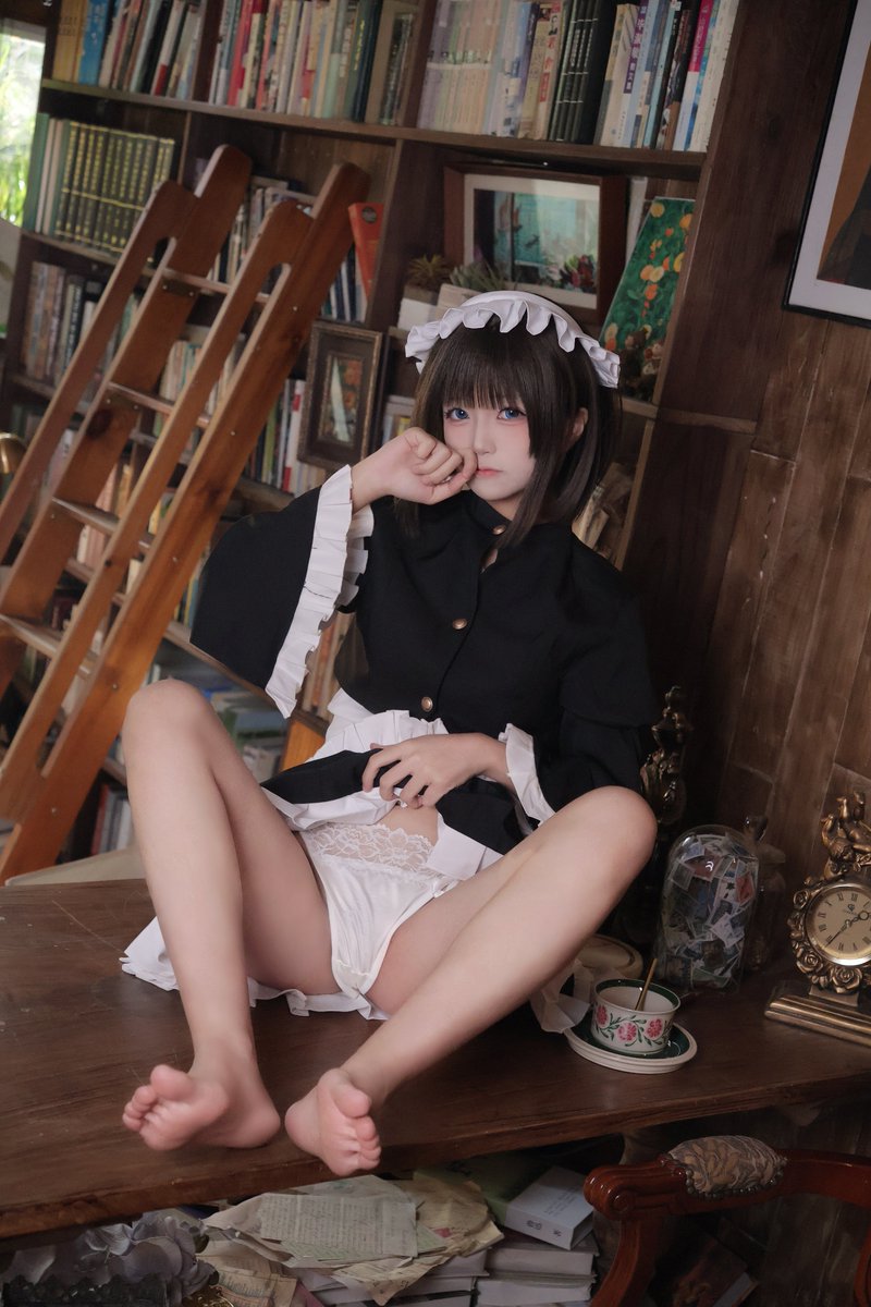 古書店の本棚の前でくつろぐクラシックなメイド服コスプレ