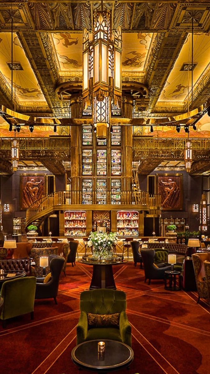 gietzschean's tweet photo. Atlas Bar in Singapore has an interior inspired by the Art Deco skyscrapers of 1920s and 1930s New York.

The room rises three storeys, with painted murals, ornate detailing and a huge central tower housing its famous gin collection. 

The scale and decoration are deliberately dramatic, inspired by the grand hotel and skyscraper interiors of the Jazz Age.

Even the dress code is strict but classy and elegant. From 5 pm, no shorts, sportswear, flip-flops, or sandals. Men must wear long trousers and closed-toe shoes.

It’s a great example of how architecture can determine the character of a place.