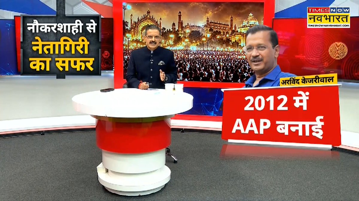 A Times Now Navbharat news broadcast features an anchor at a desk, with a graphic showing Arvind Kejriwal and Hindi text stating 'नौकरशाही से नेतागिरी का सफर' (Journey from bureaucracy to politics) and '2012 में AAP बनाई' (Founded AAP in 2012).