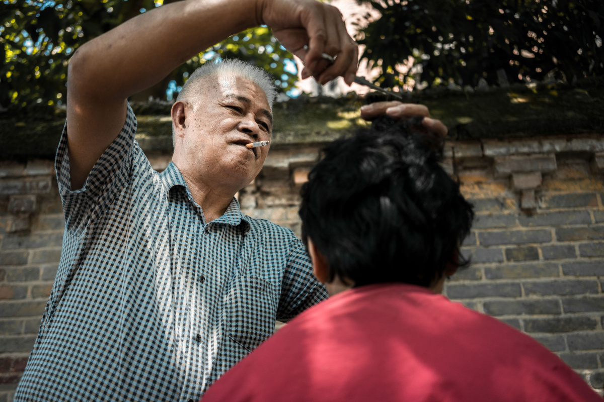 MurielScro4n's tweet photo. Caught this fleeting street moment: an old barber setting down his comb to share a laugh with a young customer, sunlight dappling their faces. Life’s best snapshots aren’t planned. https://t.co/llJXVwKgjK