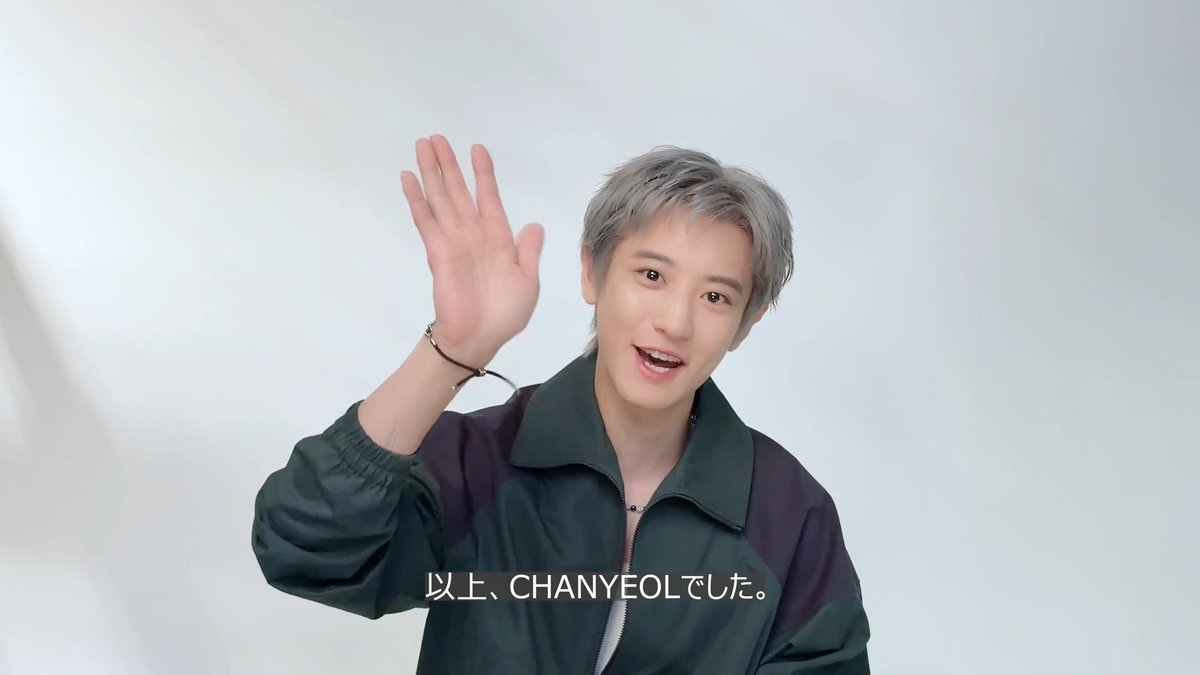 A young man with silver hair, identified by the subtitle "以上、CHANYEOLでした。" (That's all from CHANYEOL), waves cheerfully at the camera while wearing a dark green and black jacket.