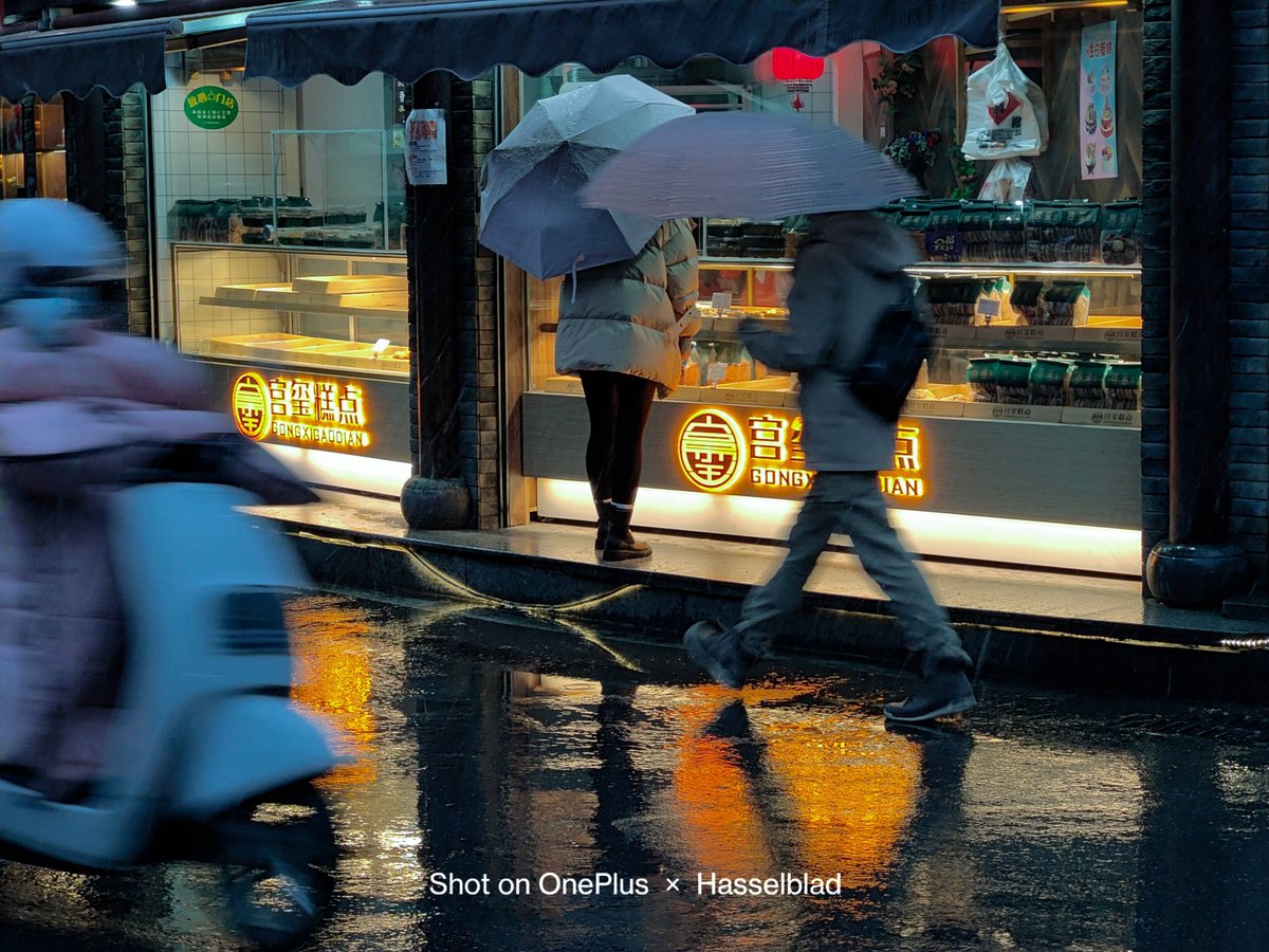 KandisFriscy's tweet photo. [A rainy street corner in the downtown, a old vending machine glowing warm light through the mist, passerby rushing by with umbrellas quietly. Just a small, cozy moment caught today.]， https://t.co/ALBn8VEFD7