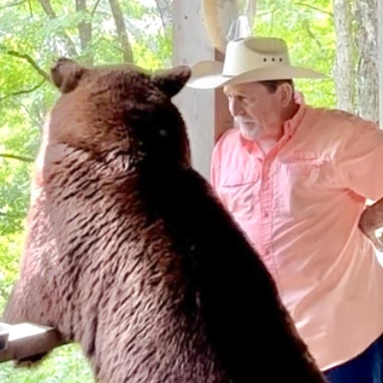 Arkypatriot's tweet photo. This one hits close to home because the man in this story is a friend of my husband.

For years he posted pictures and stories about this black bear. Hershel had become a regular part of his Facebook page, and there were plenty of pictures of the two of them together in NW Arkansas. Then somebody turned him in.

Their friendship really took hold in the summer of 2022 when Hershel showed up badly injured from a fight with a larger bear. He could hardly walk on one leg and had a gaping wound on his neck. My husband’s friend fed him, medicated him and helped him recover. Hershel survived and carried a large scar from that fight.

He never claimed Hershel was a pet. Hershel was a wild bear that would take off when unfamiliar vehicles or people showed up. But he trusted this particular man, and anyone who saw the pictures over the years could see there was an unusual bond between them.

On June 29, four Arkansas Game and Fish officers came to his home. They told him Hershel was considered a danger and would have to be removed. He strongly disagreed with their assessment, but he also knew he had violated the rules by feeding him.

Now Hershel is gone. His friend believes Arkansas Game and Fish either trapped or killed him, although he doesn't know for certain what ultimately happened to him.

People can argue about feeding wildlife, and I understand why those laws exist. But I also understand why this hurts. He found an injured bear, helped him survive, and for several years that bear kept coming back to the one human being he trusted.

Somebody saw those Facebook posts and turned him in. Now there won't be any more pictures of Hershel showing up to visit his old friend.

That's a pretty damn sad ending to a remarkable friendship.