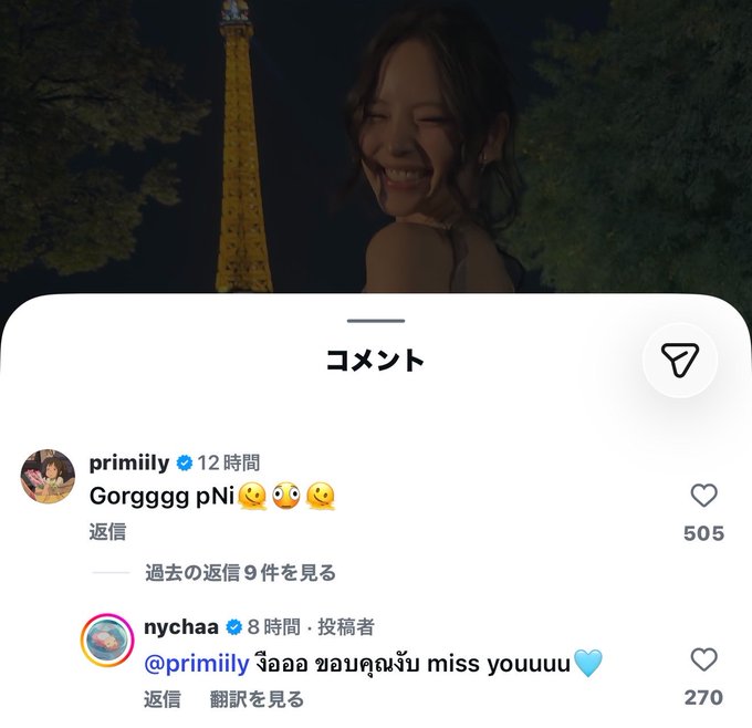 A screenshot of an Instagram comment section in Japanese, showing comments from user 'primlily' saying 'Gorgggg pNi' with 505 likes, and 'nychaa' saying '@primlily ฮอลา ขอบคุณจัง miss youuuu' with 270 likes, over a background of a smiling woman at night near the Eiffel Tower.