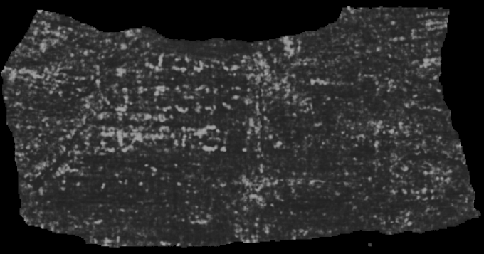 A dark, weathered artifact or scroll with faint, illegible markings or text etched into its rough surface.