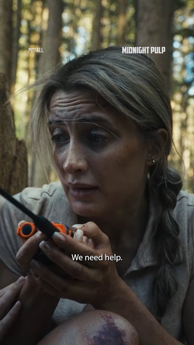 A cinematic still showing a dirty, distressed woman in a forest holding an orange walkie-talkie, with the subtitle 'We need help.' and the text 'PITFALL' and 'MIDNIGHT PULP' at the top.