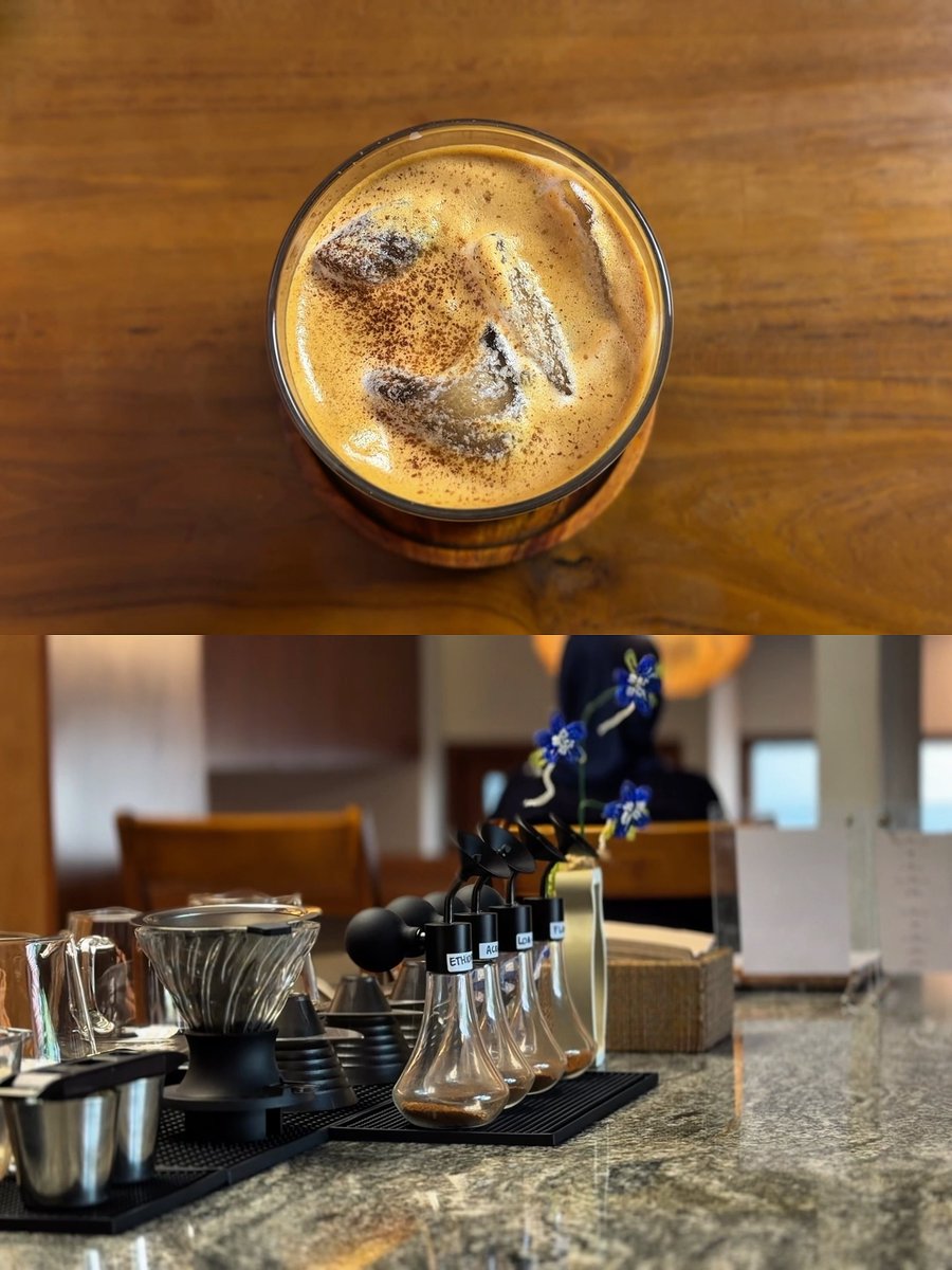 A top-down view of an iced coffee with cocoa dusting in a glass, paired with a shot of the coffee station featuring labeled syrup bottles (ETHIO, ASI, LO) and brewing equipment, both captured casually on a phone.