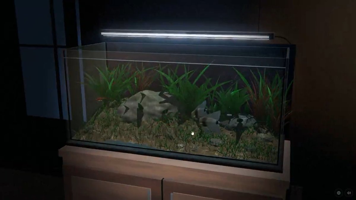 An aquarium illuminated by an LED light bar sits in a dimly lit room, containing green plants, rocks, and a few fish in a sandy tank.