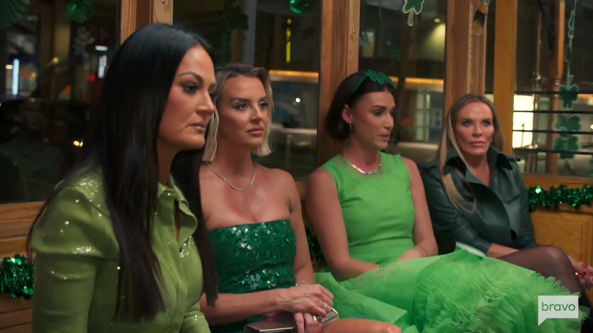 Four women sitting side by side at what appears to be a St. Patrick's Day gathering, with some wearing green outfits and a shamrock headband, and a Bravo network logo in the corner.