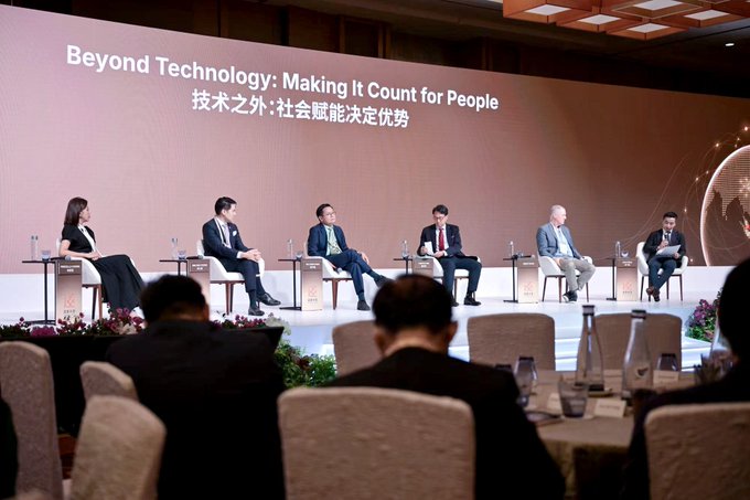 A panel discussion at a conference with the banner 'Beyond Technology: Making It Count for People' (技术之外:社会赋能决定优势) featuring seven speakers seated on stage in business attire.