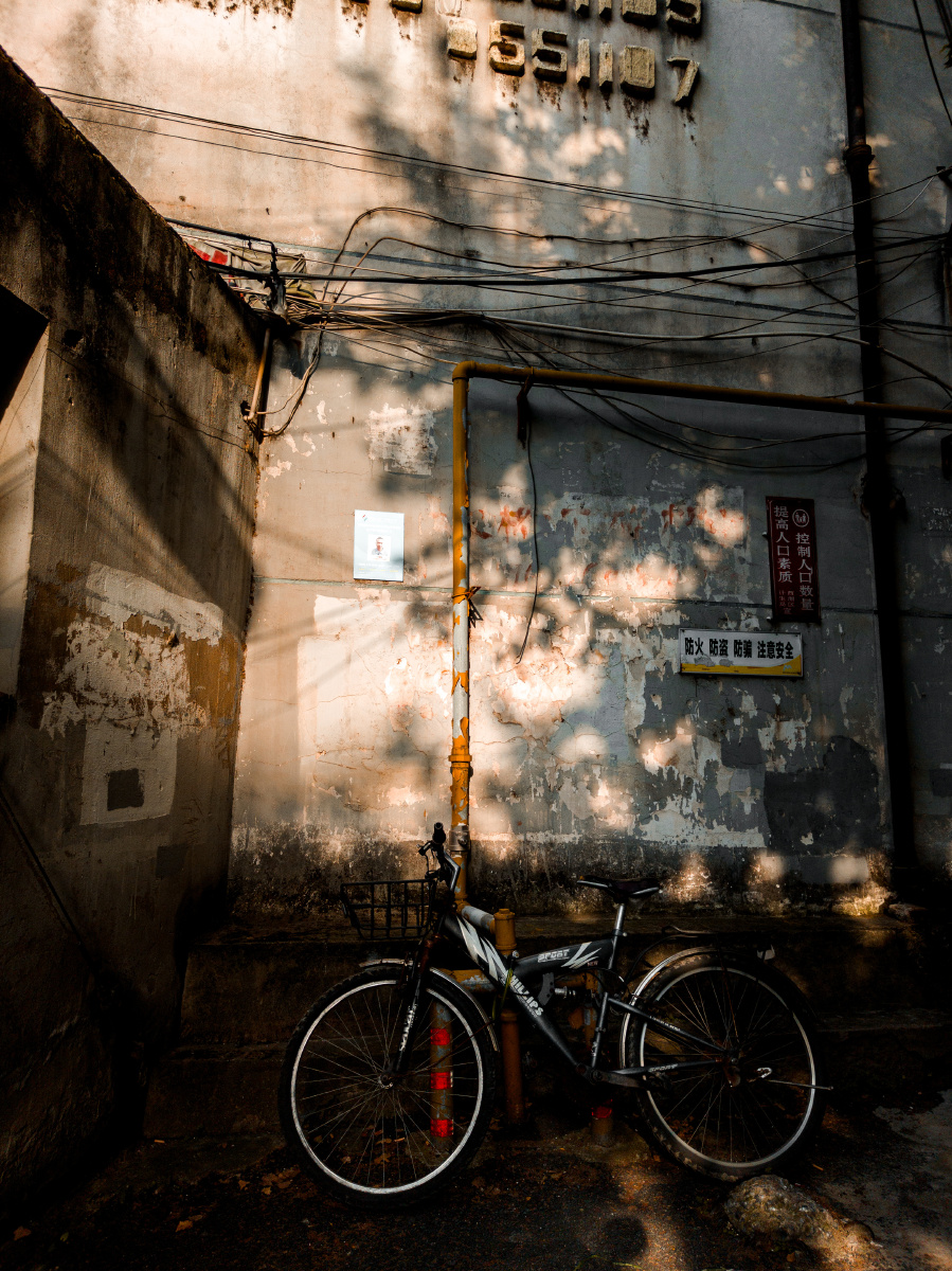 Jeffreyfauwf's tweet photo. Una instantánea callejera al atardecer, luz cálula sobre una pared de azulejos, una bicicleta olvidada apoyada en el muro. https://t.co/thrW8w66KE