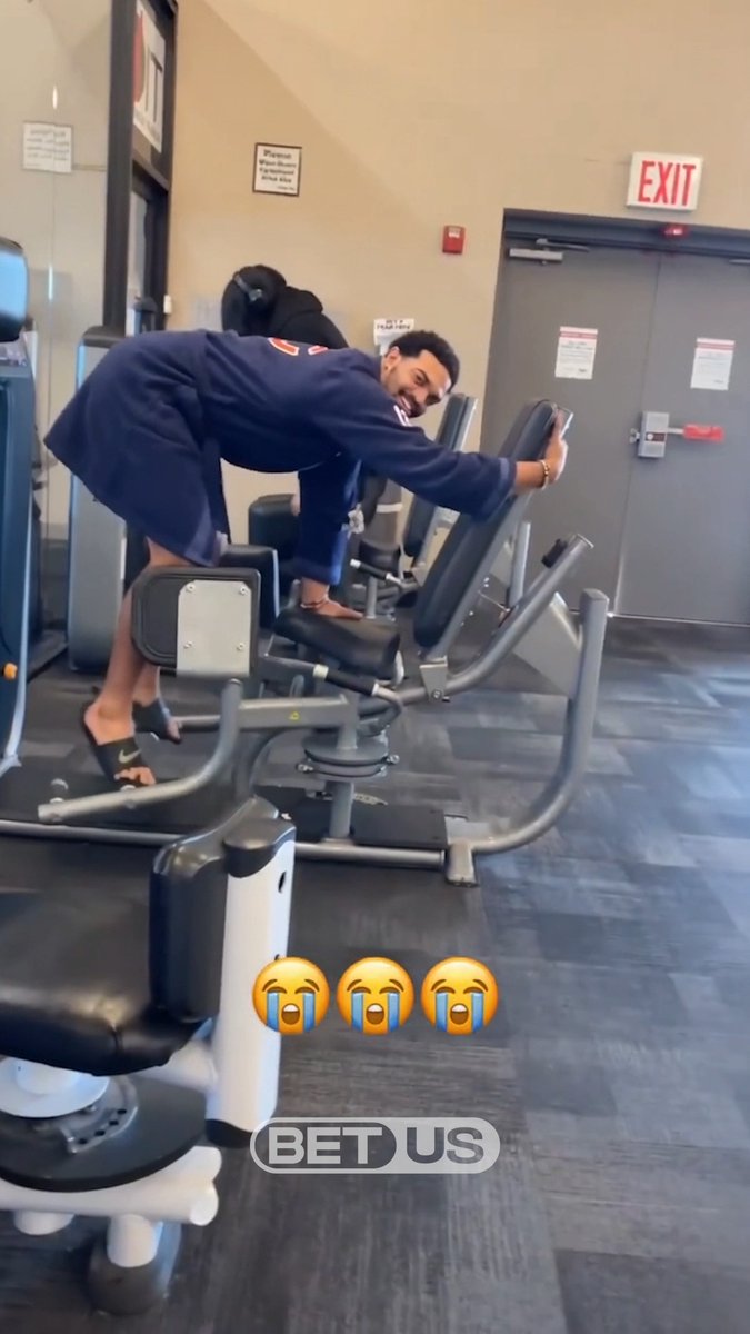 A man in a navy Bears sweatshirt is bent over on a gym machine, laughing at the camera, with three "face with tears of joy" emojis and a "BET US" logo overlaid on the video. The clip humorously suggests Caleb Williams is urgently working on his comeback after watching Case Keenum struggle at quarterback for the Bears against the Eagles.