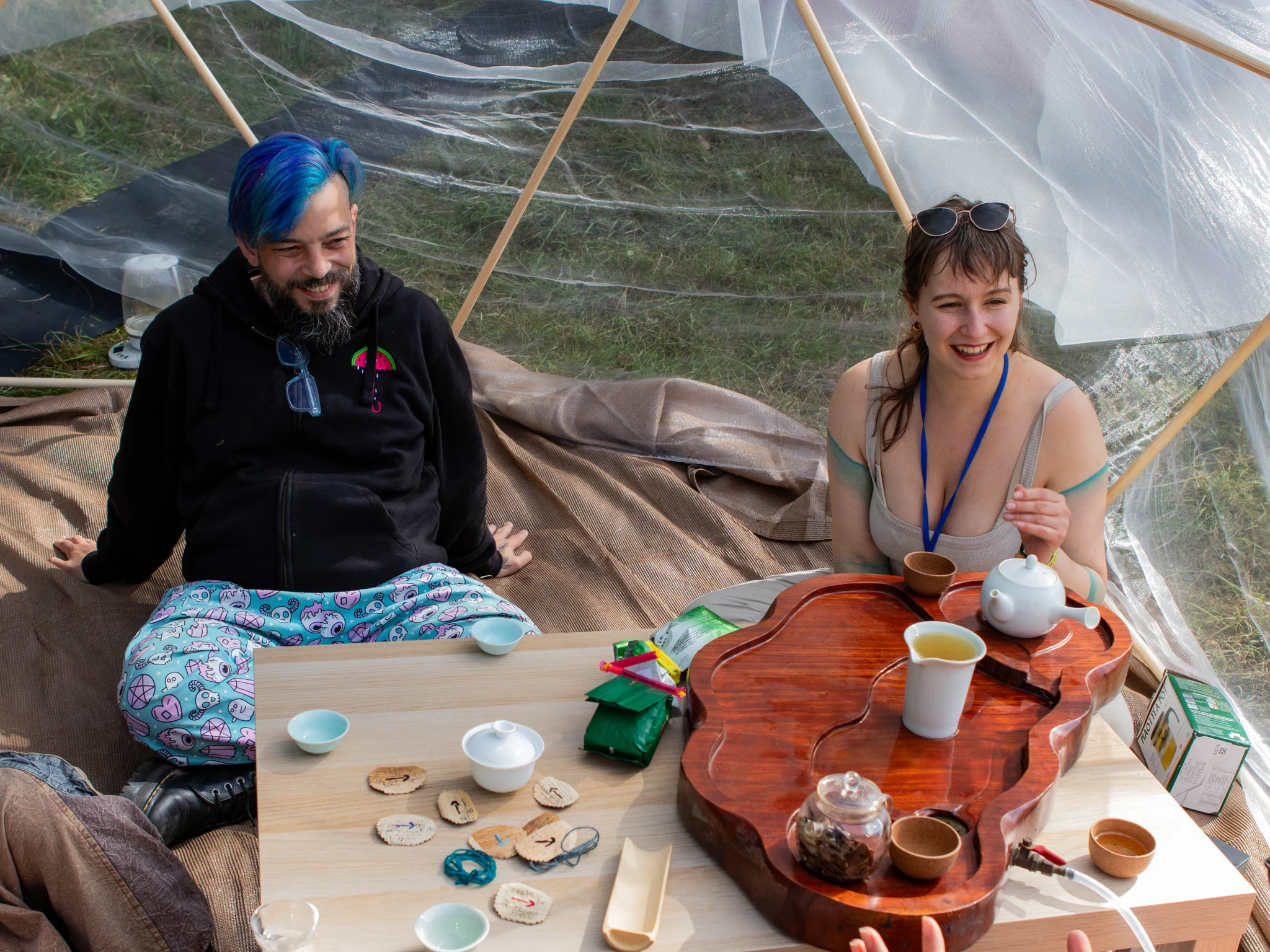 Two participants smiling and sitting around a table during the Tea cerimony at DWeb Camp 2026
