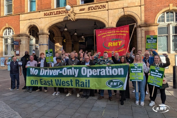 RMT union members rally outside Marylebone Station holding banners reading "No Driver-Only Operation on East West Rail" and "For Driver-Only Operation East-West Rail" from the National Union of Rail, Maritime and Transport Workers, opposing DOO implementation on the new East West Rail route—a protest that aligns with the post's frustration over delays to EWR service launches in the Winsford/Oxford-Milton Keynes corridor.