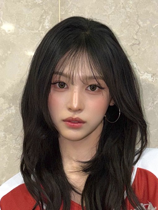 A young woman with long dark hair and a soft, natural makeup look gazes directly at the camera, complementing the post's affectionate sentiment that she "looks so good, for real." She's wearing a red top with white accents, and her delicate features and rosy cheeks enhance the warm, admiring tone of the caption.